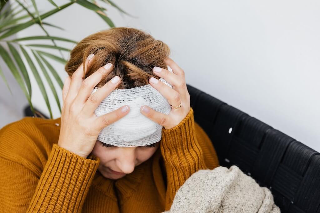 woman holding her bandaged head