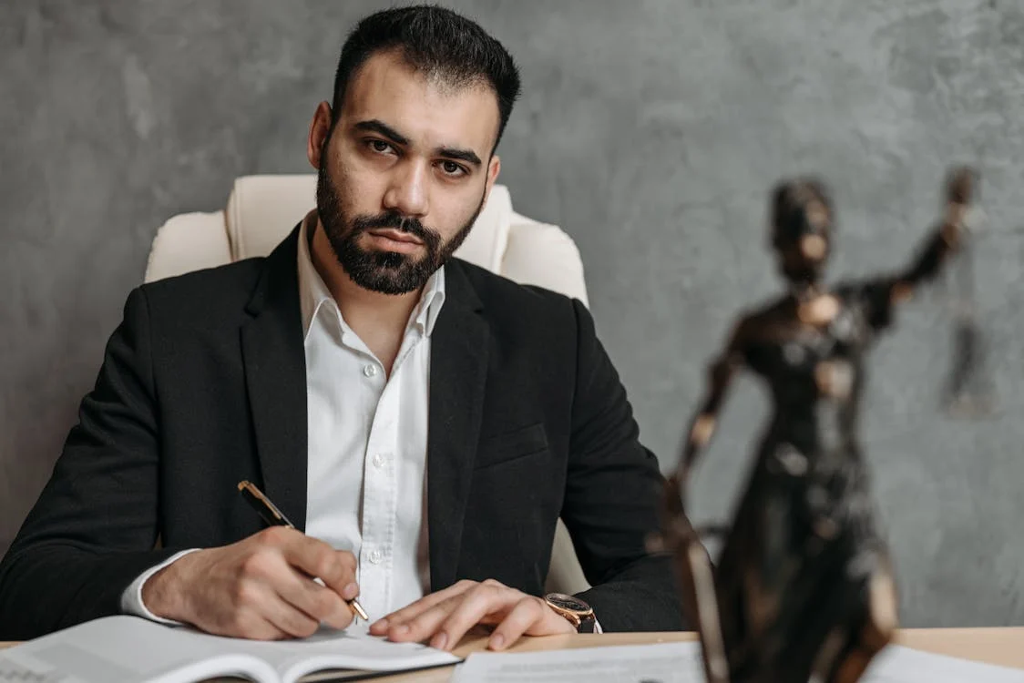 lawyer sitting at desk behind lady justice statue