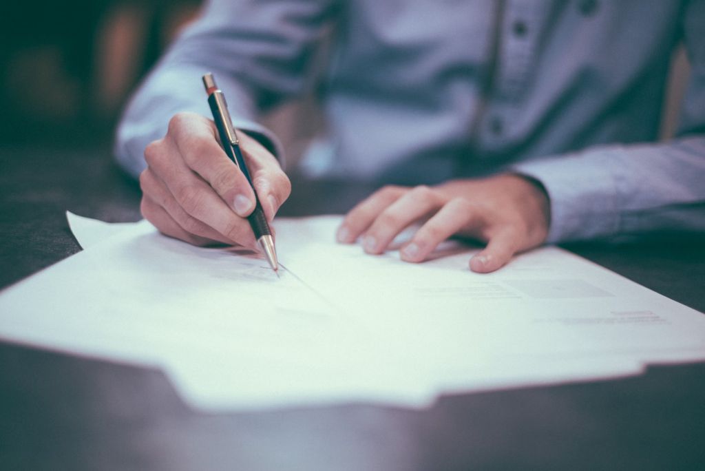 person in button-up shirt writing documents