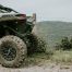 mud covered ATV parked next to wire fence overlooking valley