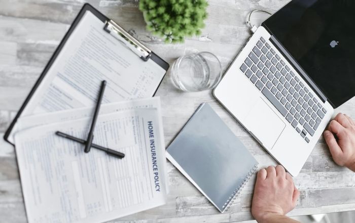 home insurance policy paperwork next to laptop and notebook on desk