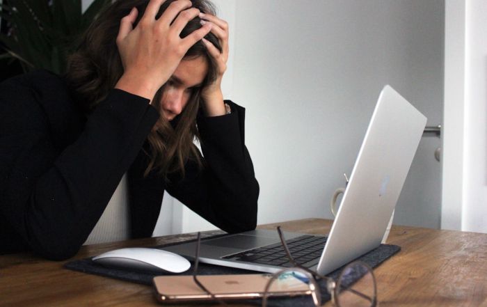 A woman holding her head in her hands looking distraught