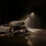 A wrecked vehicle, taped off, alone on the side of street light lit road
