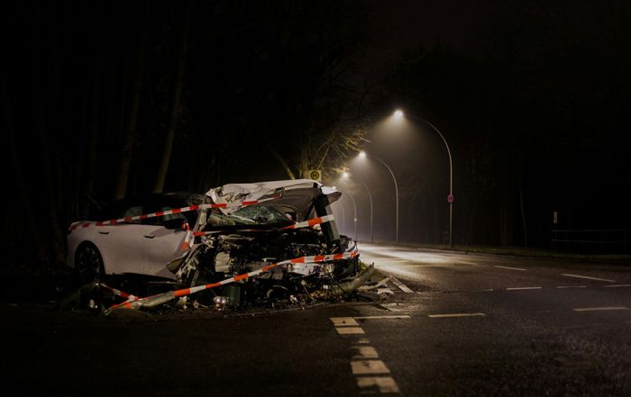 A wrecked vehicle, taped off, alone on the side of street light lit road