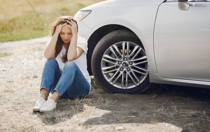 A woman looking upset, sitting outside of her car