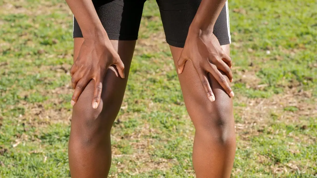 An athlete grasping his knees in pain