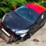 A red and black crashed car on the side of the road