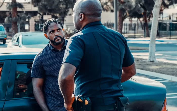 A police officer talking to a man beside a car on a sunny street